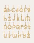 Gold alphabet initial earrings arranged in a grid on a light cream background, each letter featuring a small diamond