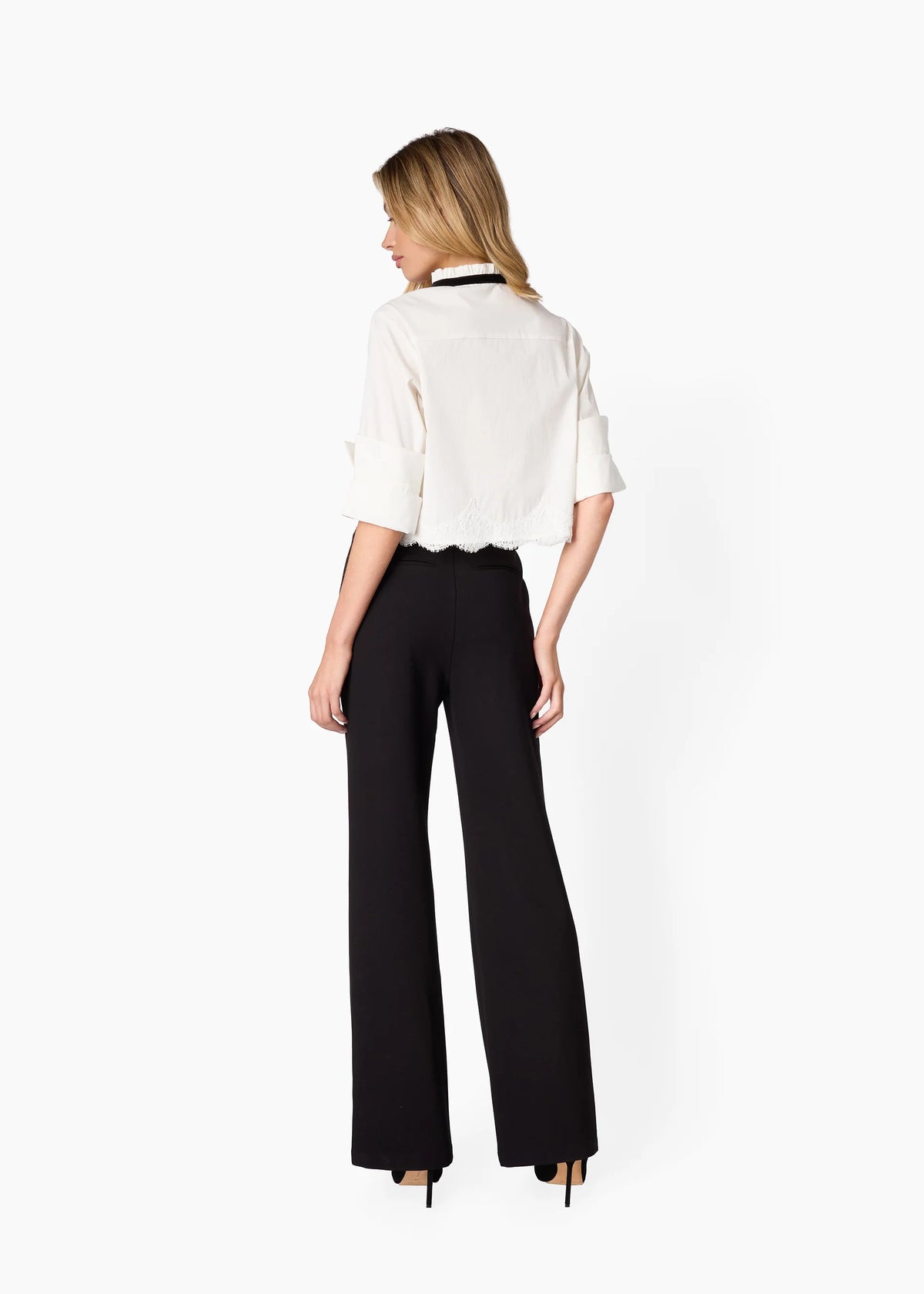 Woman wearing a white blouse and black pants on a white background