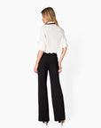 Woman wearing a white blouse and black pants on a white background