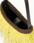 Close-up of a handbag with a bright yellow feathered exterior, a dark brown leather trim adorned with iridescent rhinestones, and a black interior.