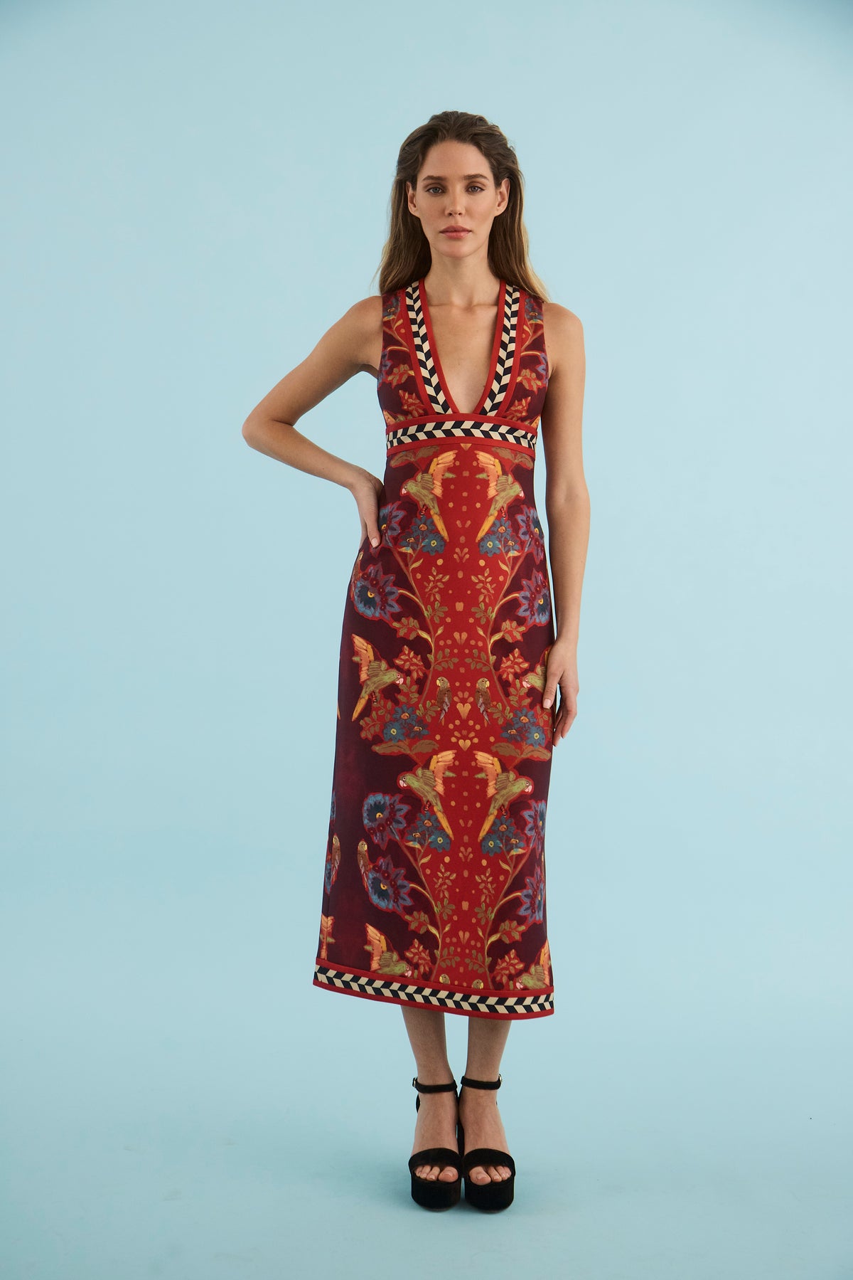 model wearing a print midi dress with black heels on a blue back ground 