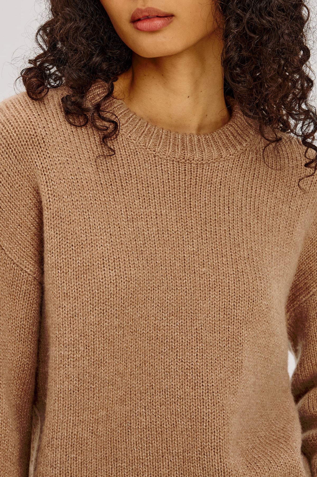 Close-up of a person wearing a brown knitted sweater with a blurred background