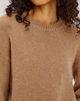 Close-up of a person wearing a brown knitted sweater with a blurred background