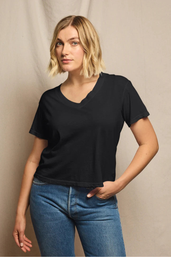 Woman wearing a black t-shirt and blue jeans against a neutral background, size L
