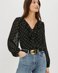 Woman wearing a black polka dot blouse and blue jeans on a white background