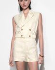 Woman wearing a cream-colored sleeveless blazer and shorts set on a white background