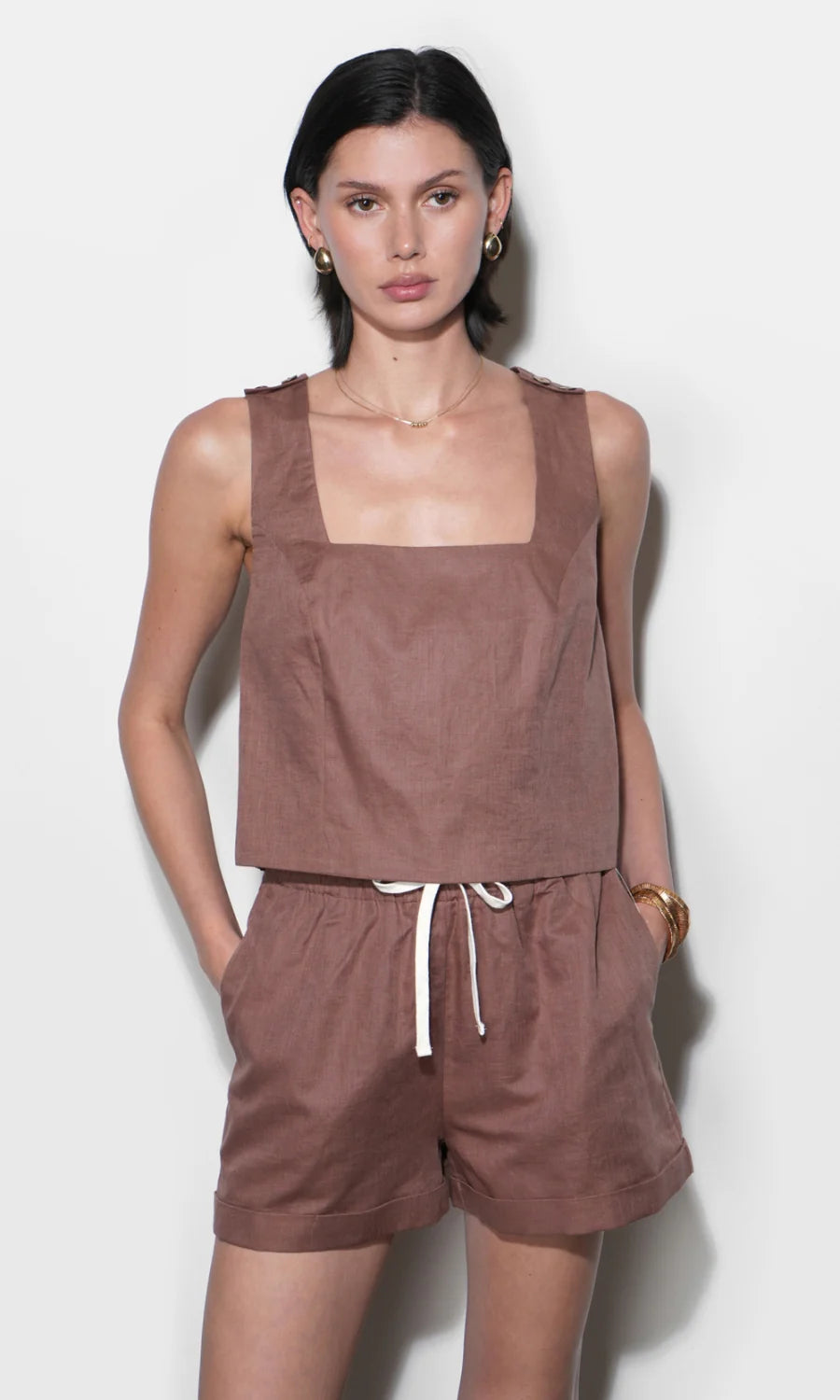 Woman wearing a brown sleeveless top and shorts set on a white background