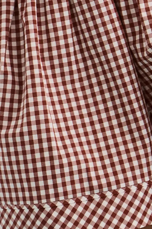 Close-up of a red and white gingham check fabric with a visible stitched hem.