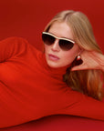 Heidi 12K Matte Black Fade Chroma + Blonde Venezia Sunglasses on model with red shirt, red background