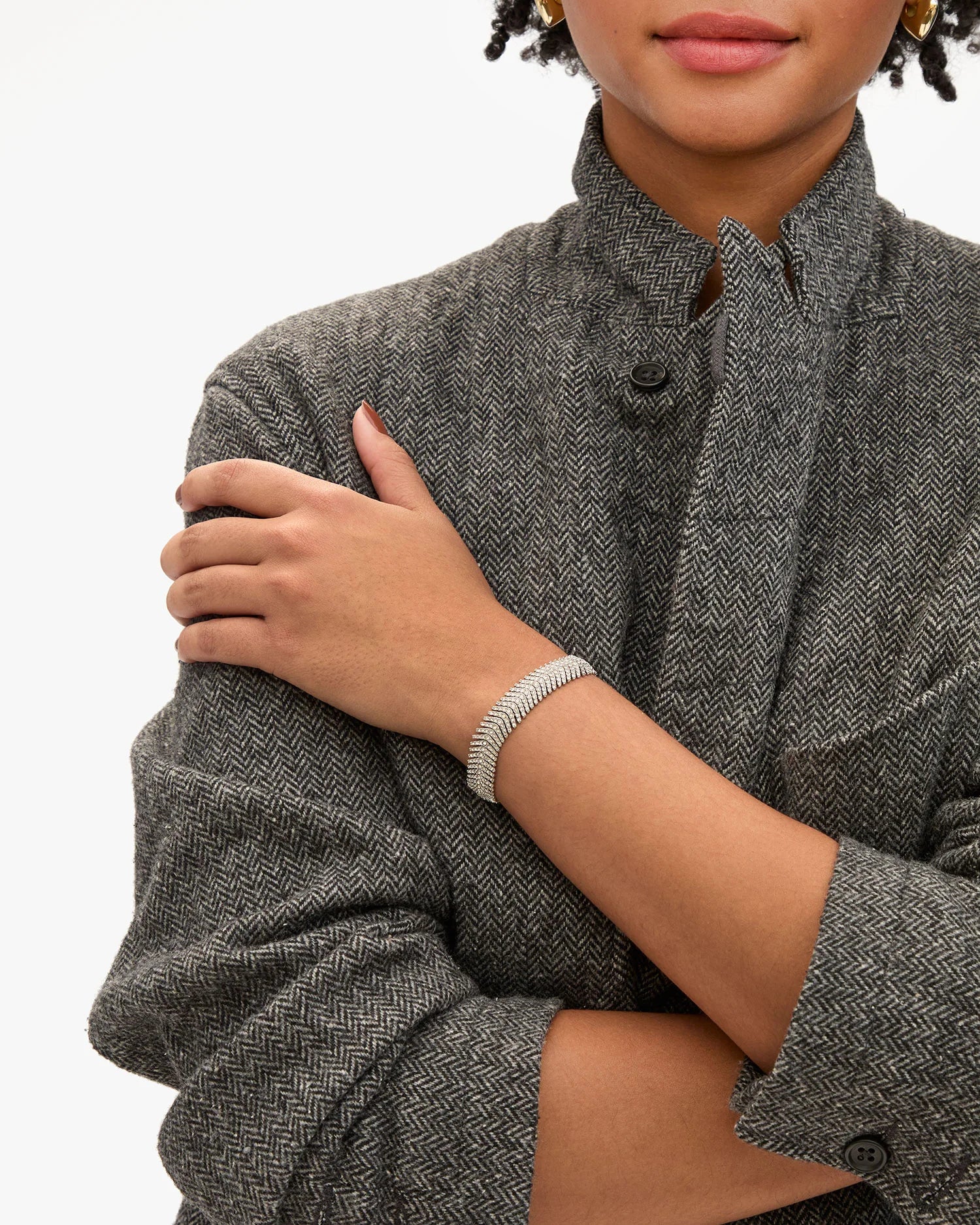 Person wearing a gray textured coat with a close-up of their arm and hand.