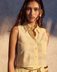 Woman wearing a light-colored sleeveless top with a textured pattern against a neutral background
