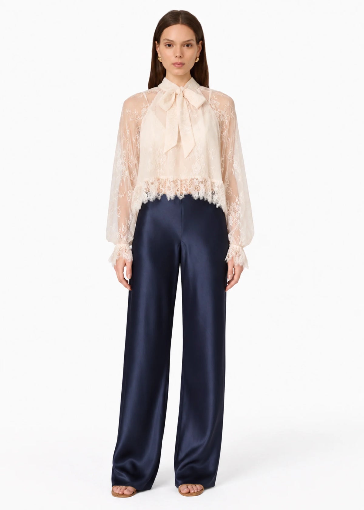 model wearing a lace tie neck long sleeve top with navy bottoms on a white background