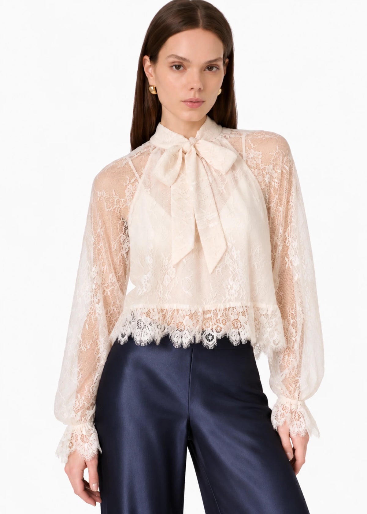 model wearing a lace tie neck long sleeve top with navy bottoms on a white background