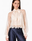 model wearing a lace tie neck long sleeve top with navy bottoms on a white background