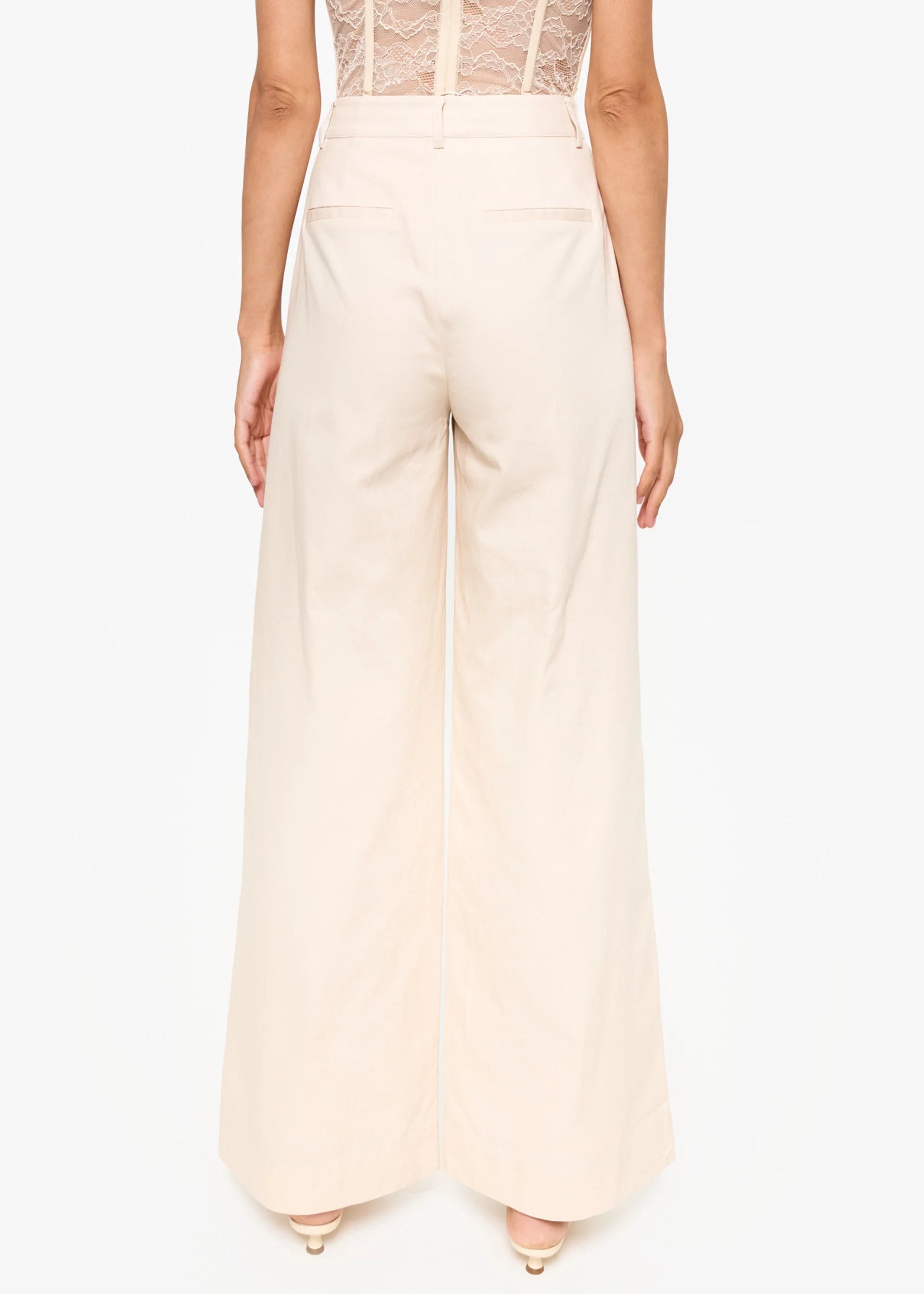 Beige high-waisted pants worn by a person on a white background back view