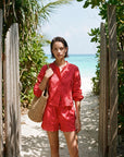 Woman in a red outfit standing on a sandy path with tropical scenery