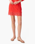Red lace-trimmed skirt worn by a person on a white background