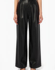 Black leather pants worn by a person on a white background