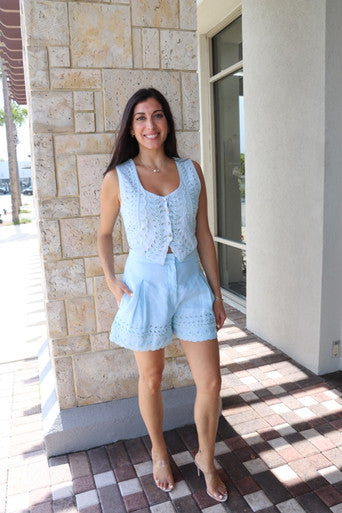 Woman in light blue outfit standing in front of a stone building.