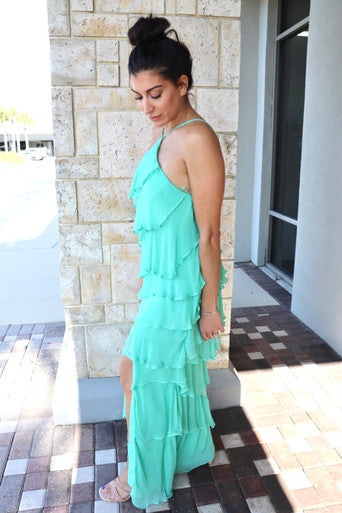Woman wearing a green dress standing on a stone patio, side view