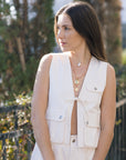 Woman wearing a white sleeveless vest with a blurred outdoor background