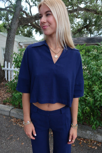 Woman wearing a blue outfit standing outdoors with greenery in the background
