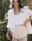 Woman wearing a white outfit with lace shorts in an outdoor setting