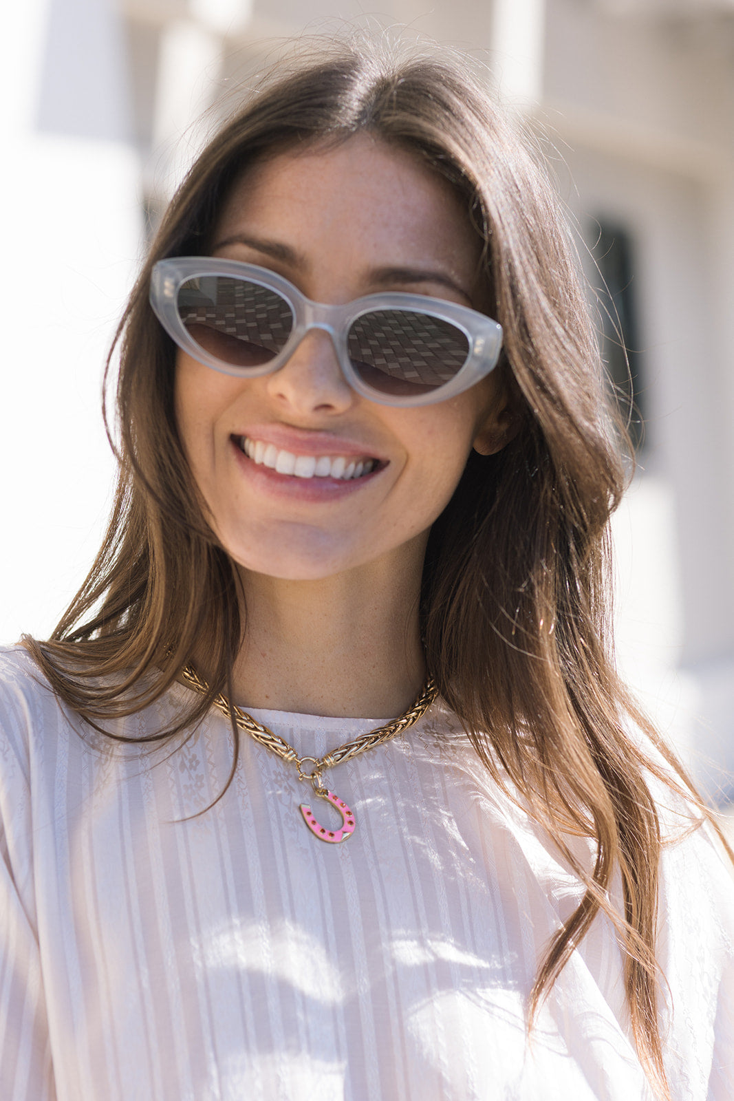 Woman wearing sunglasses and Chunky Wheat Chain Necklace with pink horseshoe charm with a blurred background
