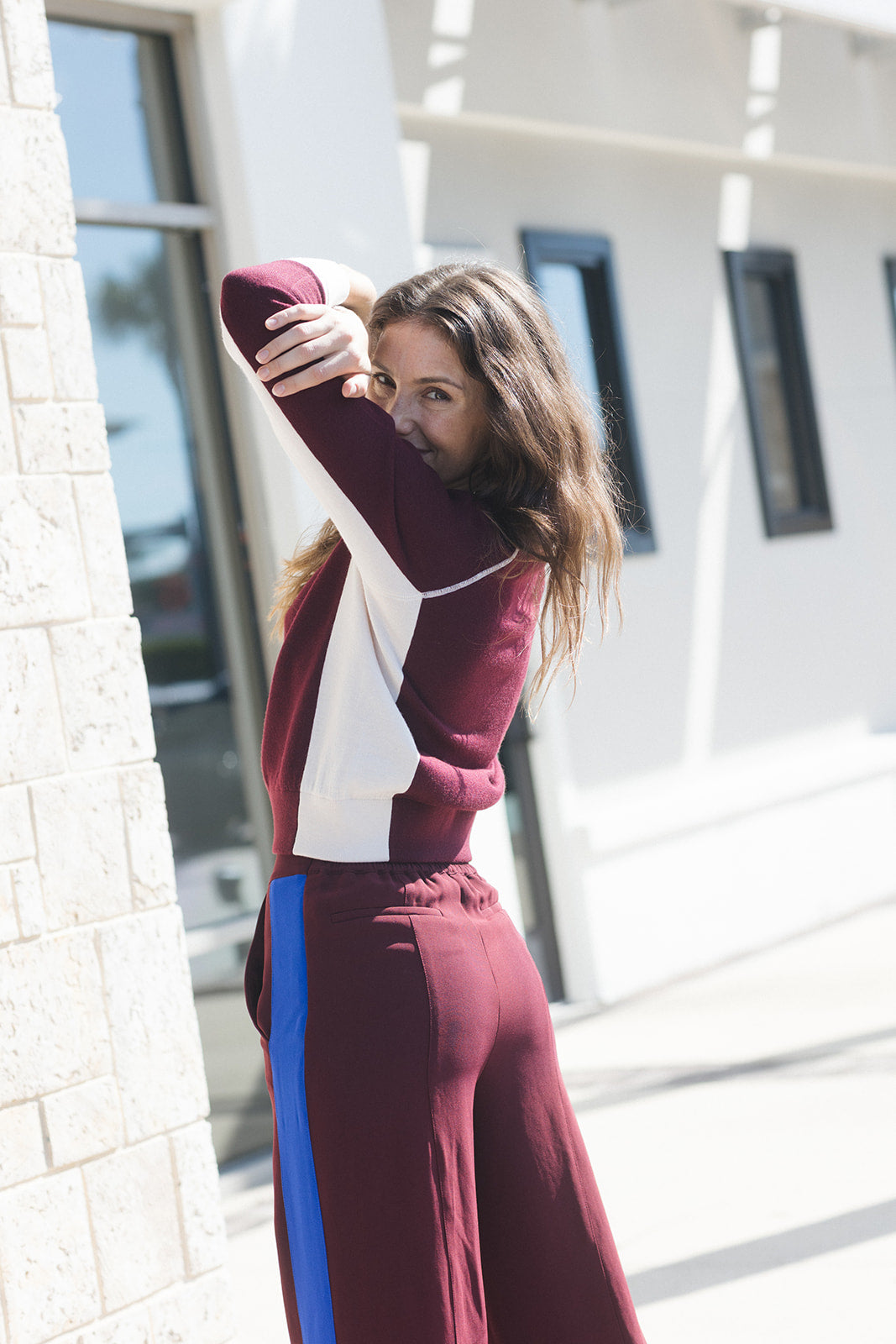 model wearing a burgundy sweater with white detail and burgundy pants with a blue stripe 
