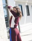 model wearing a burgundy sweater with white detail and burgundy pants with a blue stripe 