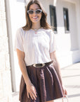 Woman wearing a white blouse and brown skirt with sunglasses outdoors.