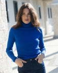 model wearing a blue turtleneck and jeans outdoors at a shopping plaza 