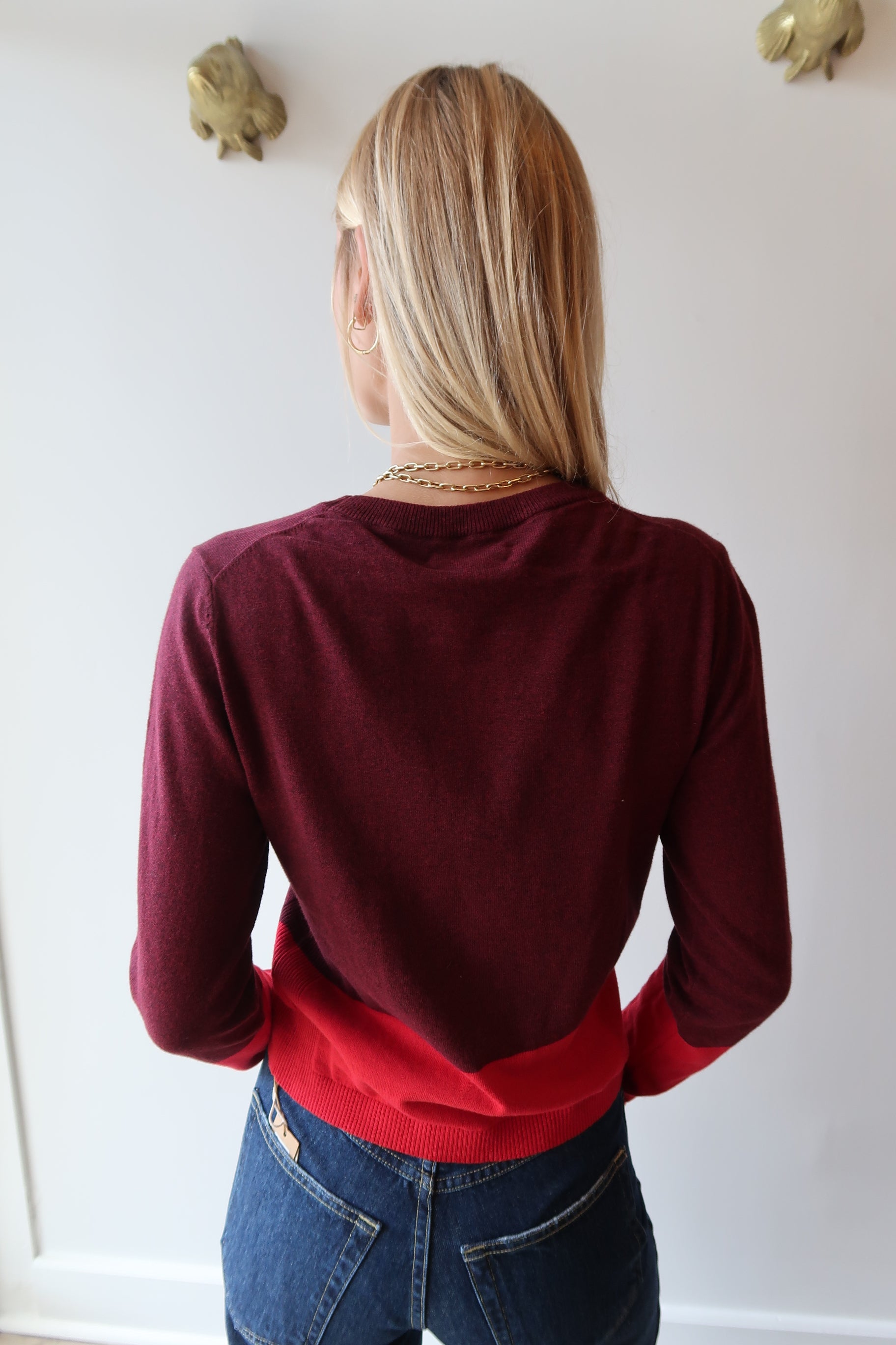 Person wearing a red sweater and blue jeans, back