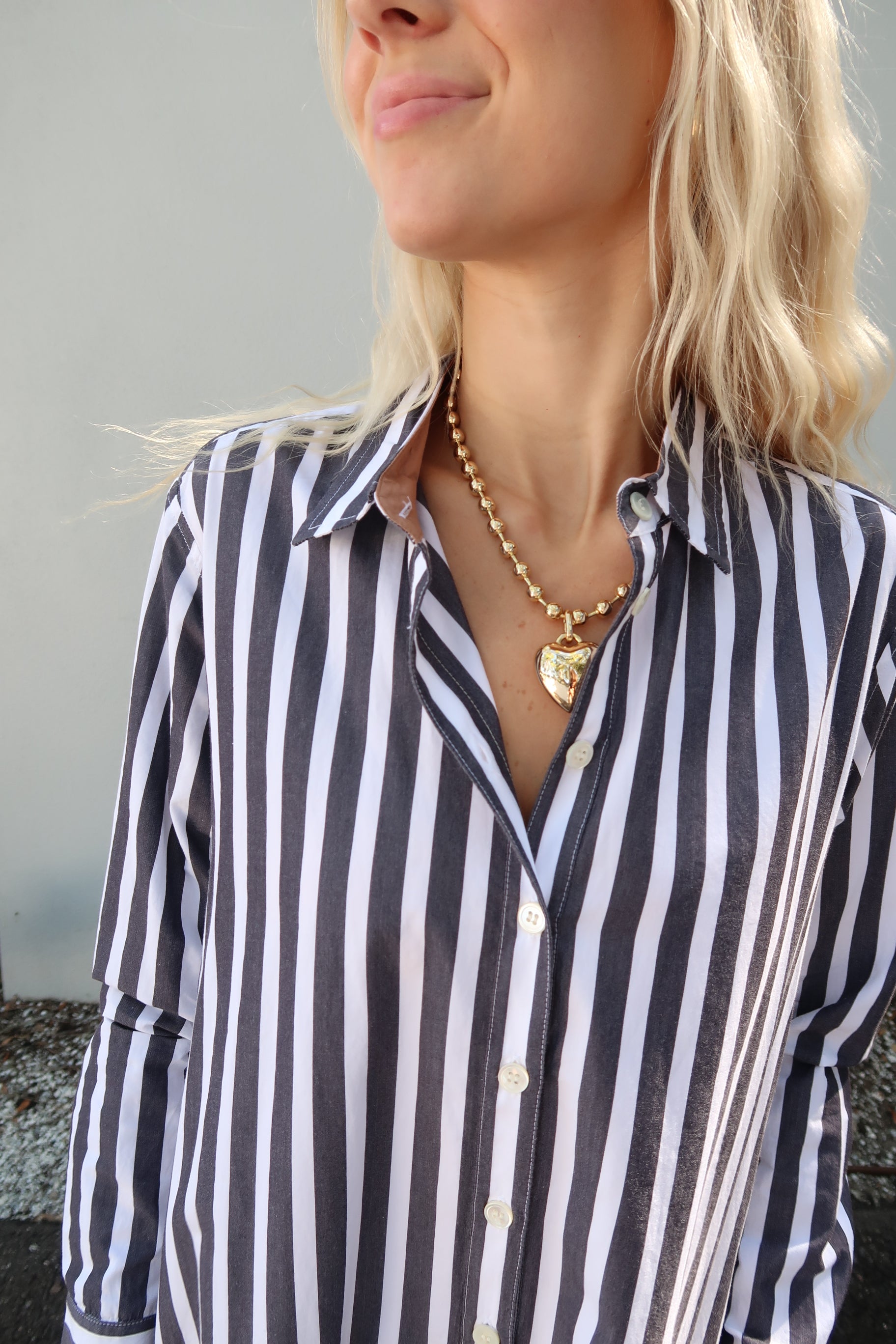 Close-up of a person wearing a grey and white striped dress with a blurred background