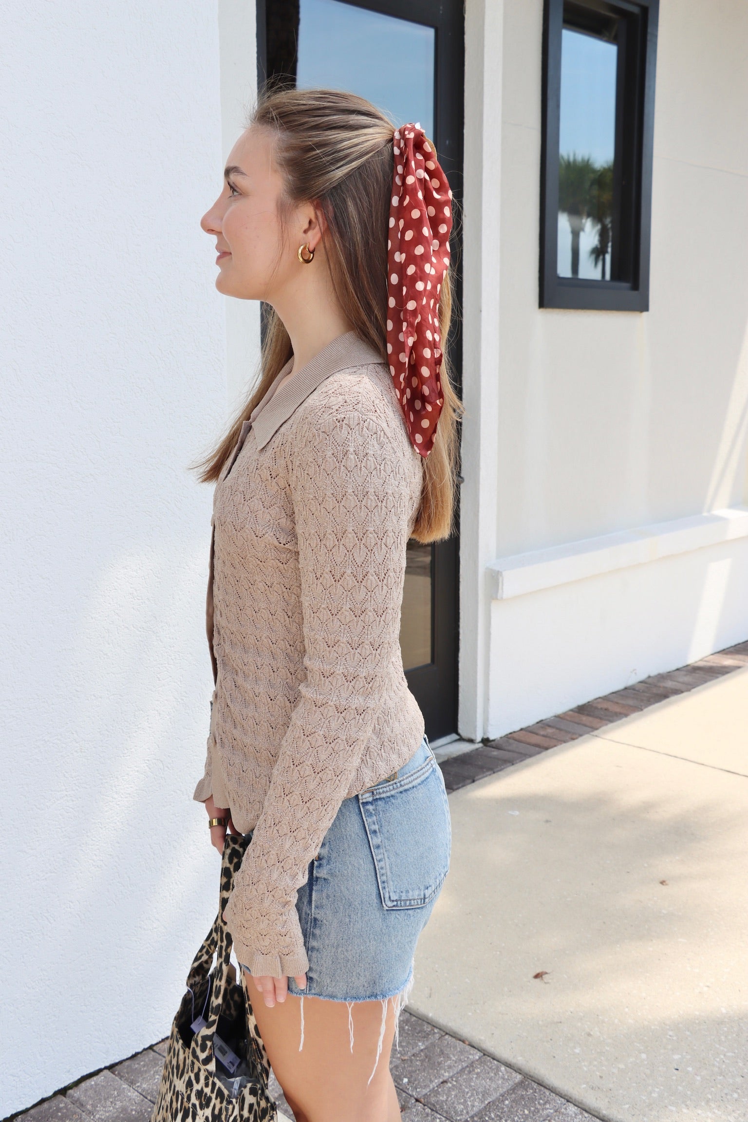 Woman with a red polka dot headscarf standing outside a building