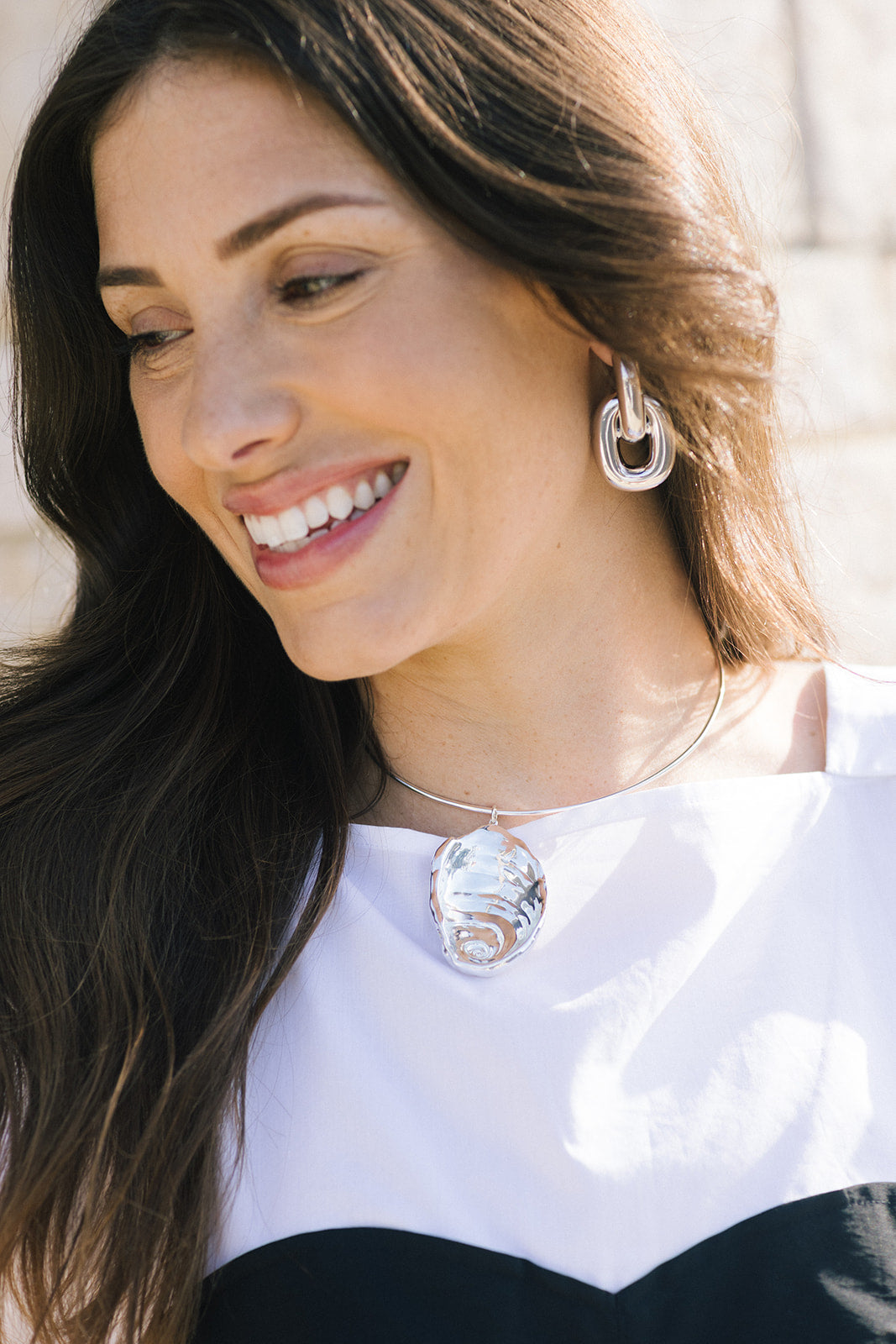 Woman wearing a silver necklace and earrings with a blurred background