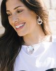 Woman wearing a silver necklace and earrings with a blurred background