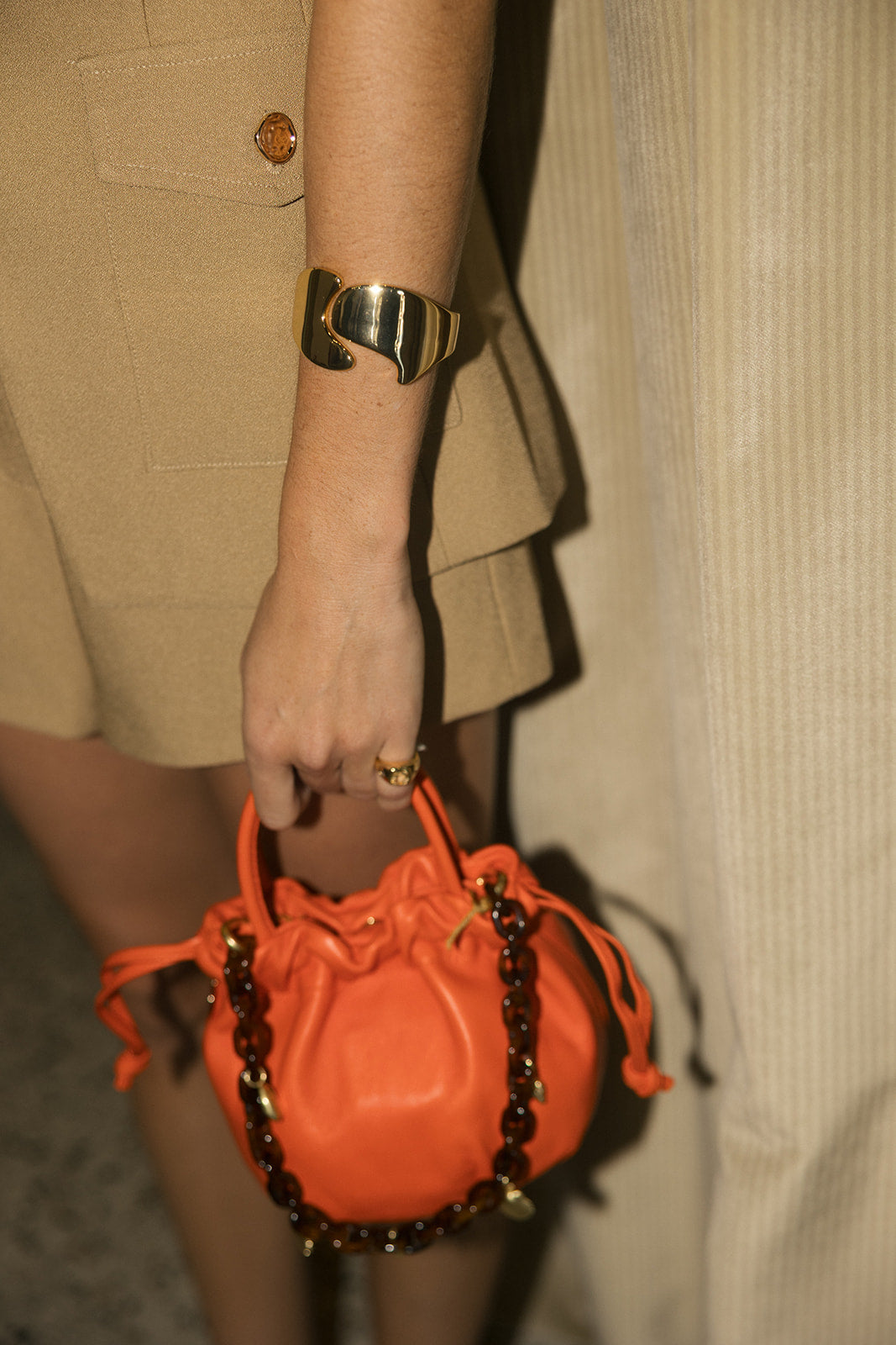 orange clare v bag with tortoise strap being held by a model 