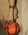 orange clare v bag with tortoise strap being held by a model 