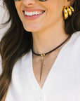 Woman wearing gold hoop earrings and collar necklace with a white top.