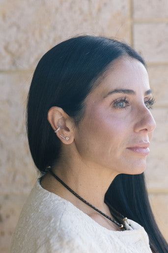 Woman with long dark hair wearing a necklace against a stone wall background wearing Make Your Move Pave Spade Post