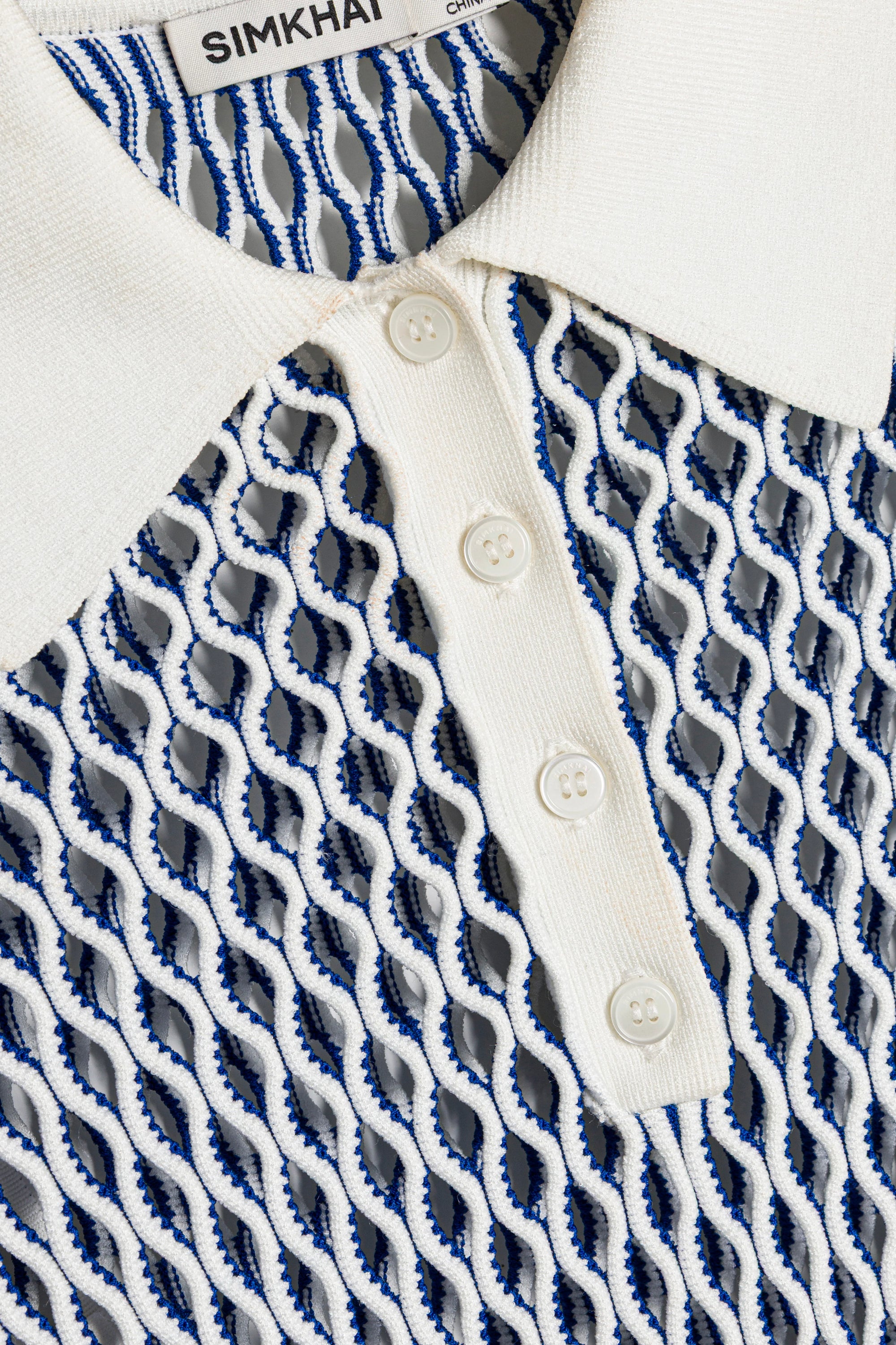 Close-up of a white shirt with blue and gray patterned collar and buttons, brand 'Simkhah' visible.
