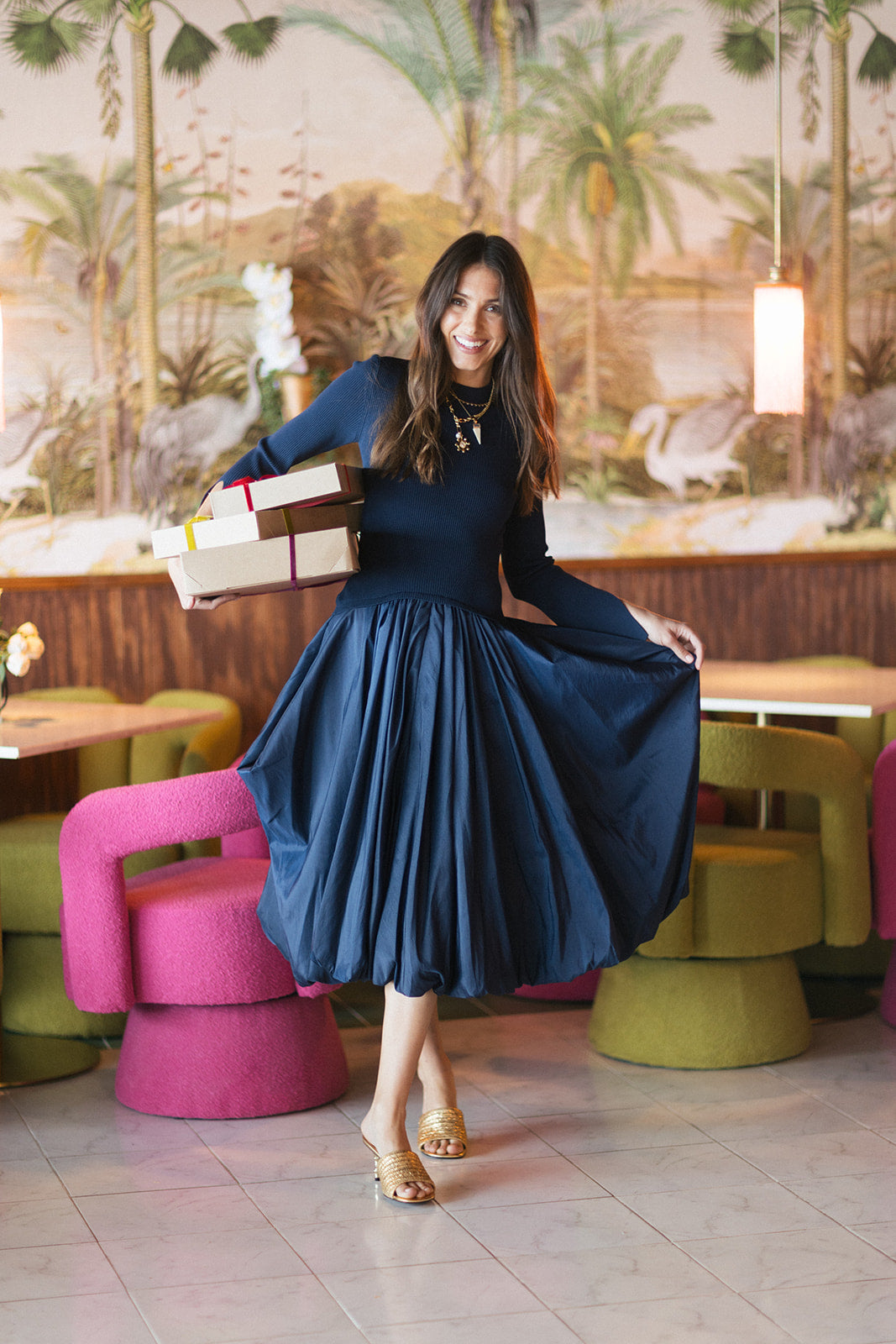 Model wearing a blue dress holding gifts with a colorful background