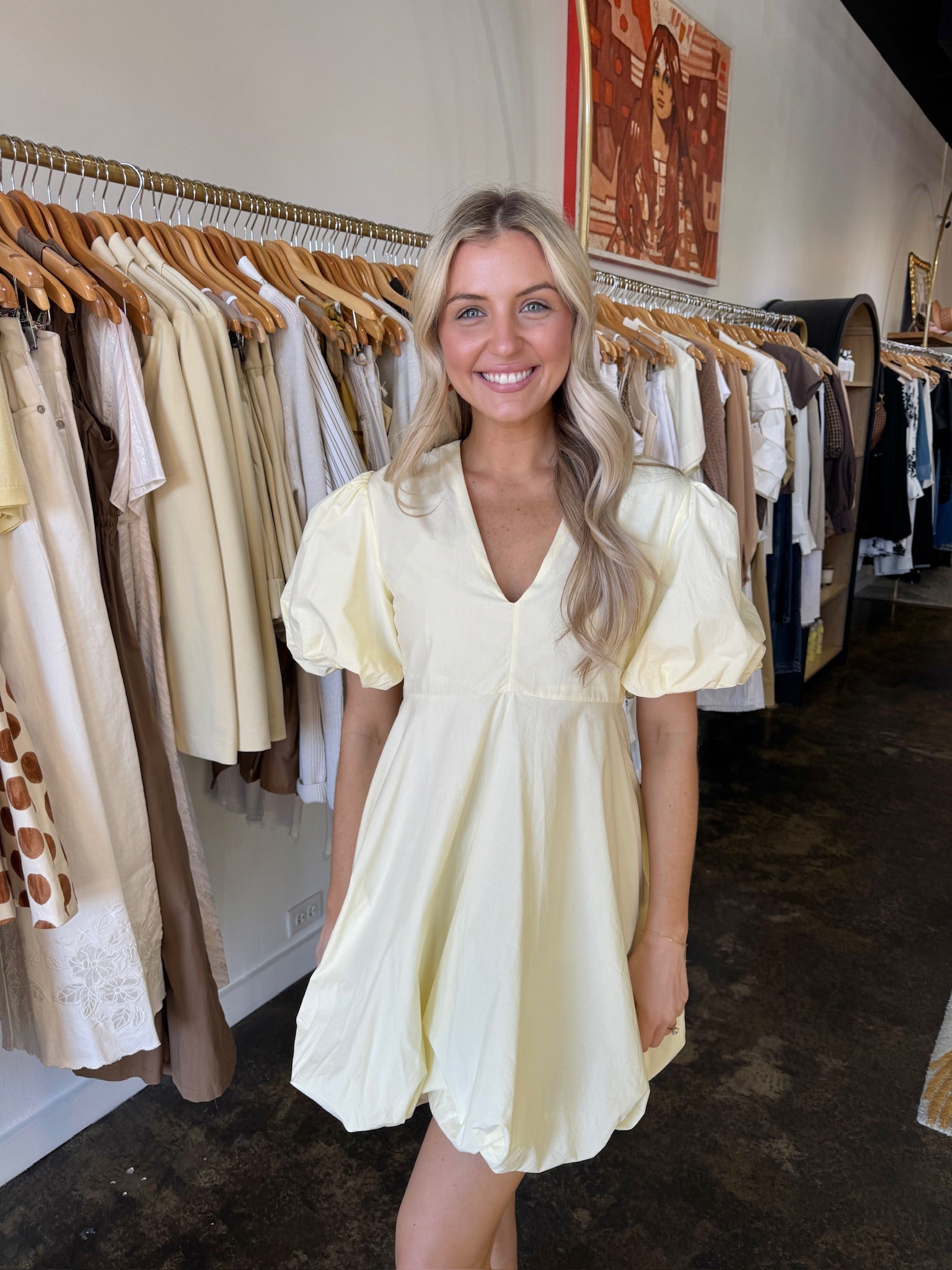 Woman wearing a light yellow dress in a clothing store.