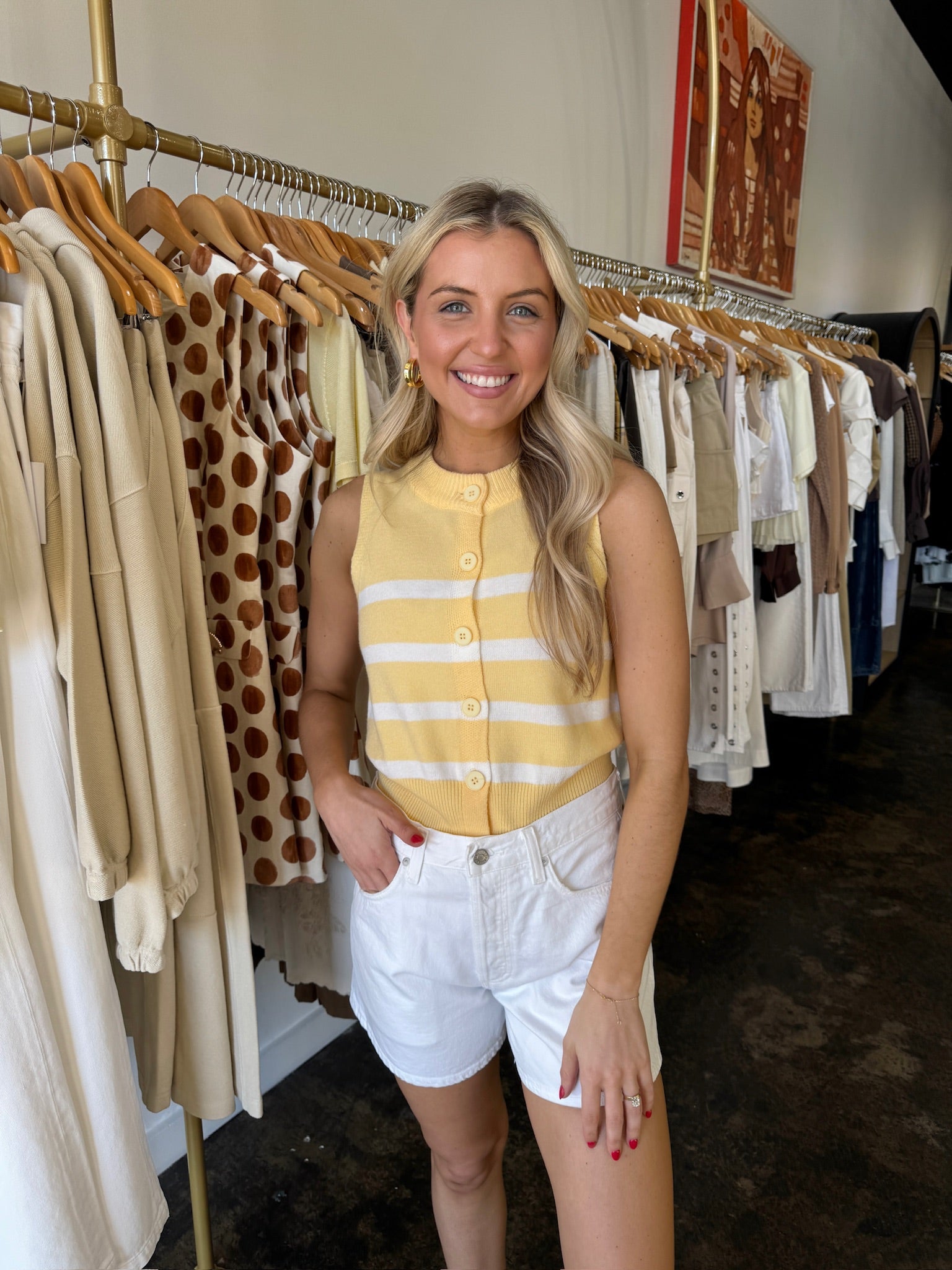 Woman in a yellow striped shirt and white shorts standing in a clothing store.