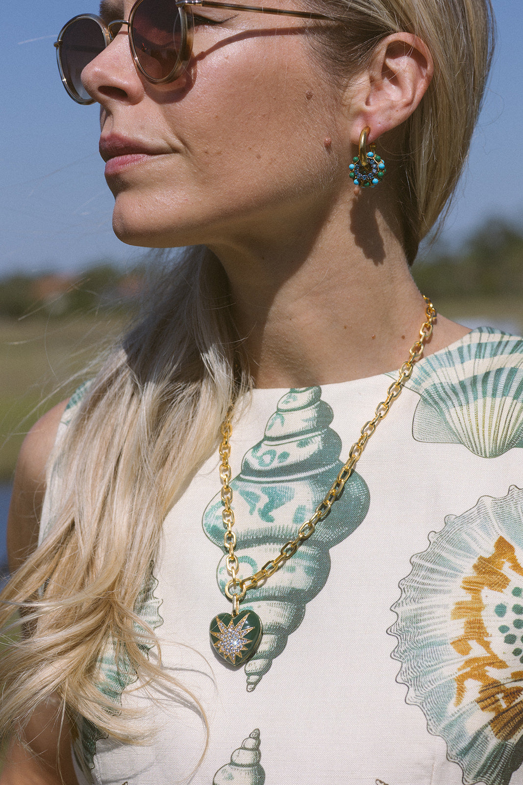 Model wearing a shirt with shells on it and a necklace with a heart pendant