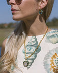 Model wearing a shirt with shells on it and a necklace with a heart pendant