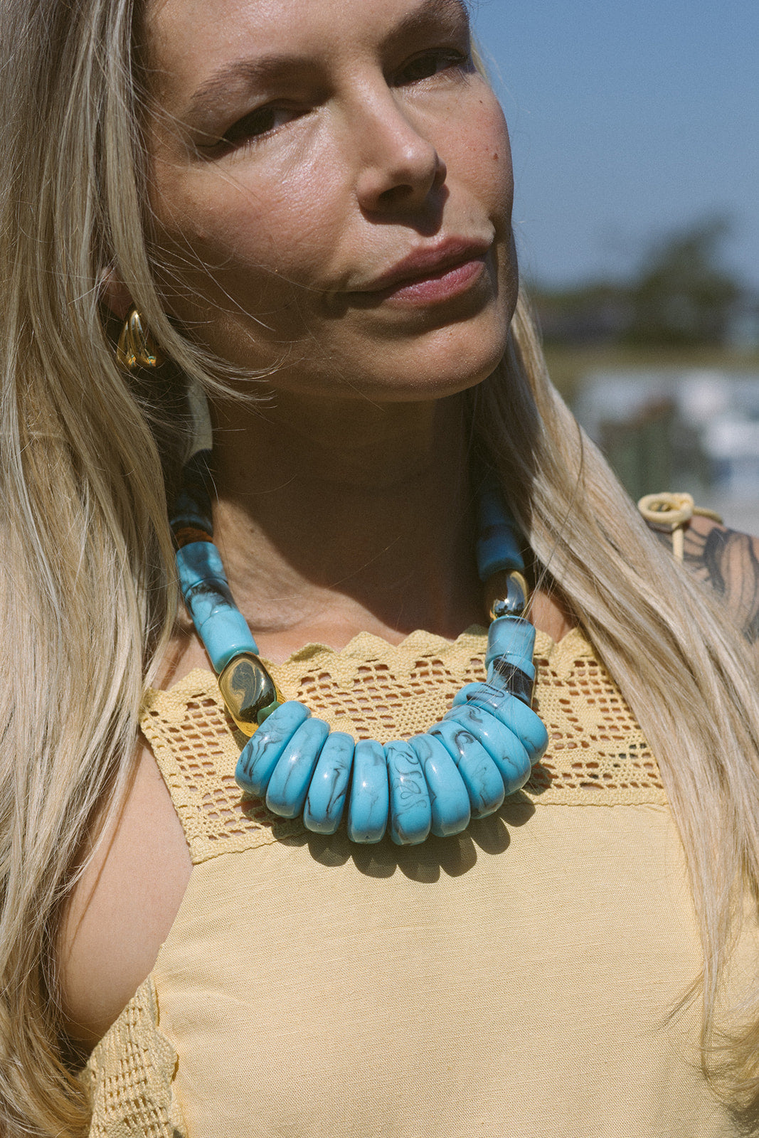 Woman wearing a turquoise necklace with a blurred outdoor background