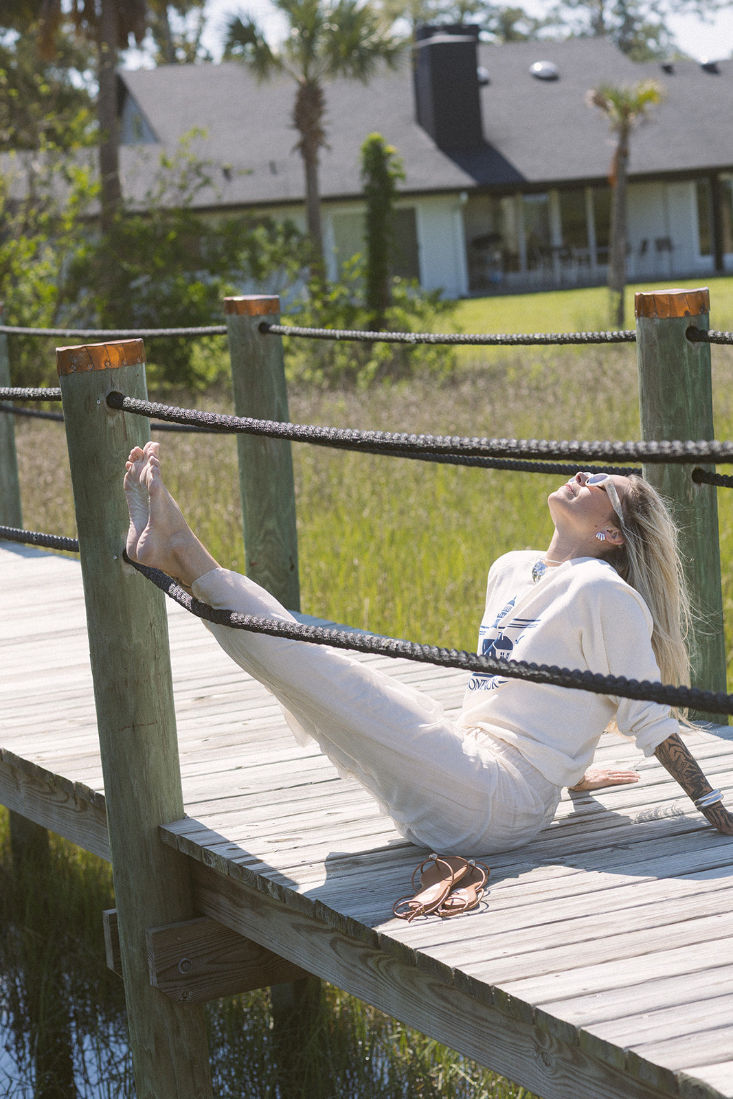 Woman sitting on a wooden dock with a scenic background wearing Strada Pants
