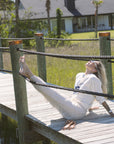 Woman sitting on a wooden dock with a scenic background wearing Strada Pants